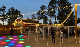 Kids hopping on glowing, colorful Sparkle Steps lights at Forest Bend Farm at dusk
